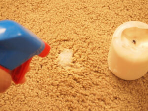 membersihkan lilin yang menempel di karpet